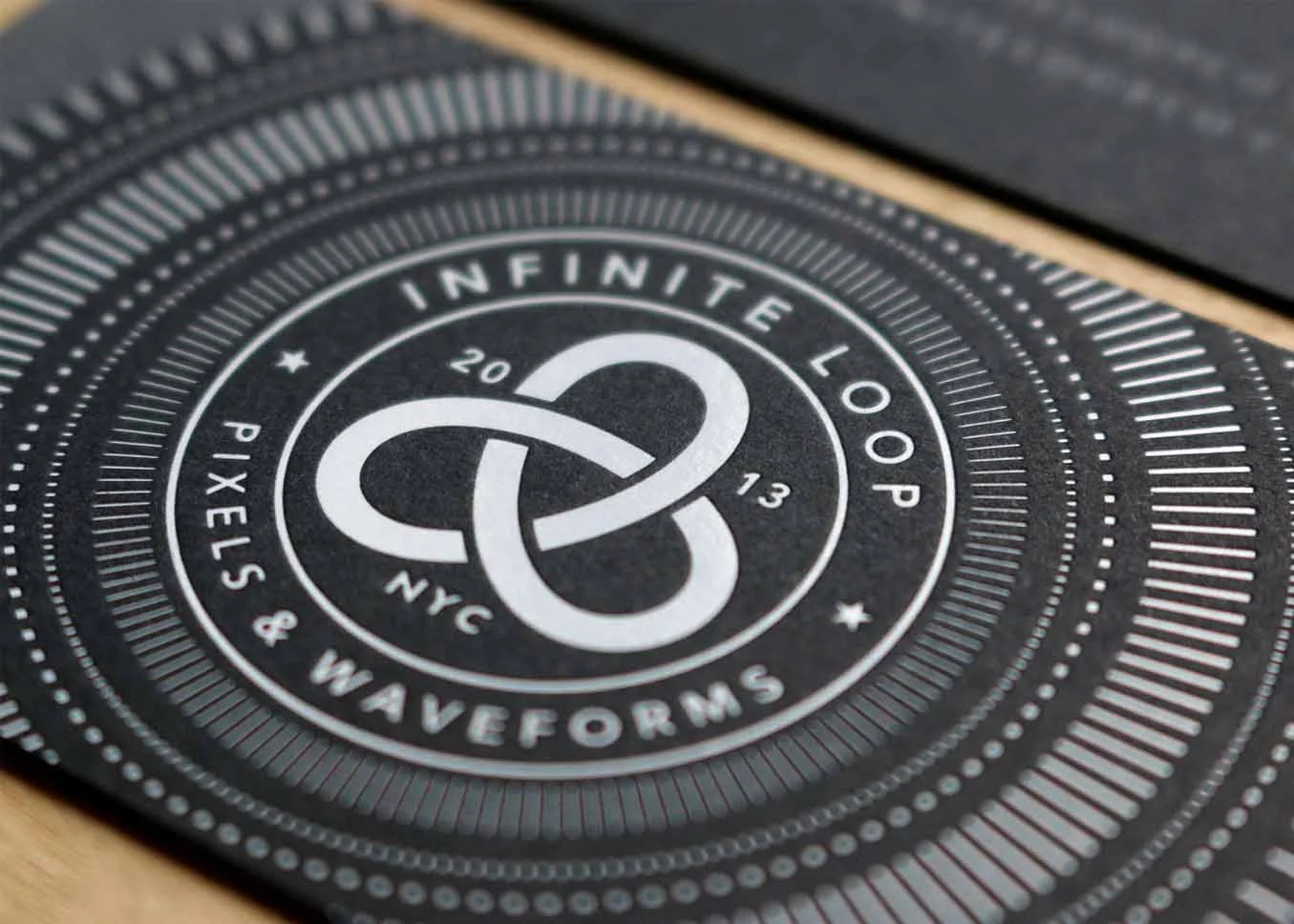 White foil stamped business cards on black paper showing deep impression detail