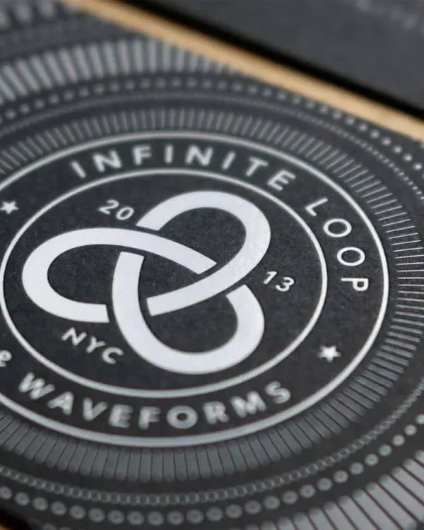 White foil stamped business cards spread across black stock showing geometric pattern detail