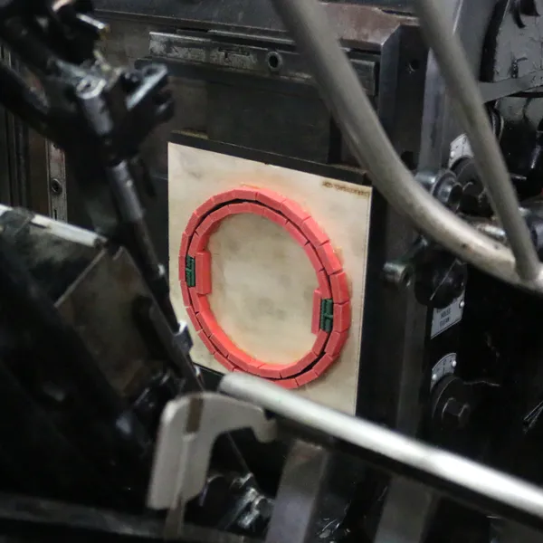 A circular steel rule die locked up in the Heidelberg press, seen through the gripper arms and guards