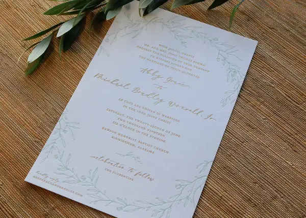 Letterpress and gold foil wedding invitation with delicate floral design on white cotton paper