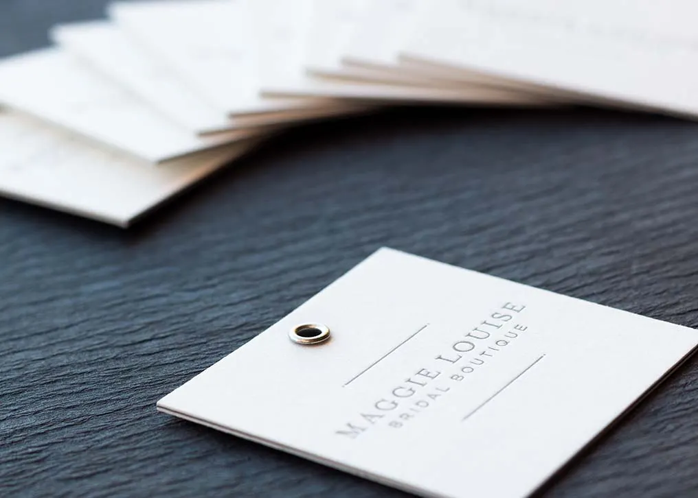 Edge view of triplexed hang tag showing grey inner sheet between white cotton layers