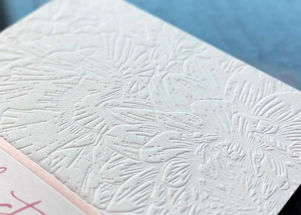 Close-up of blind deboss floral pattern pressed into cotton paper on menu top
